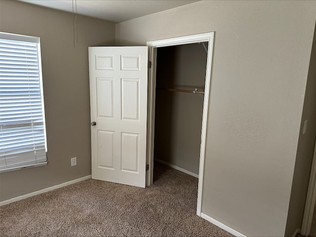 unfurnished bedroom with a closet and dark colored carpet