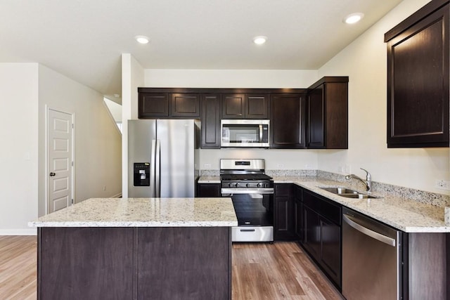 kitchen featuring sink, light hardwood / wood-style flooring, light stone countertops, and appliances with stainless steel finishes