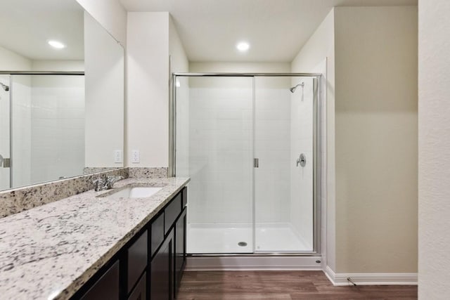 bathroom with walk in shower, vanity, and hardwood / wood-style floors