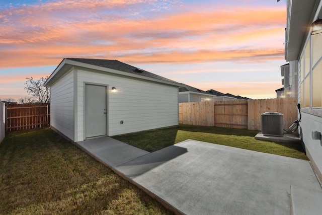 outdoor structure at dusk featuring cooling unit and a lawn