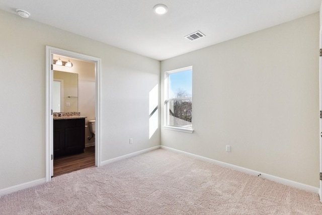 unfurnished bedroom with light colored carpet and ensuite bathroom