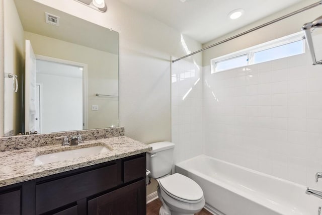 full bathroom with tiled shower / bath combo, vanity, hardwood / wood-style floors, and toilet