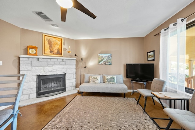 living room featuring a stone fireplace and ceiling fan