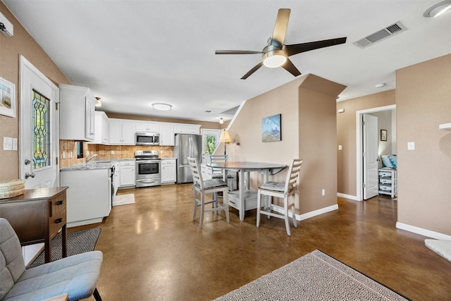 kitchen featuring backsplash, white cabinets, ceiling fan, appliances with stainless steel finishes, and light stone counters