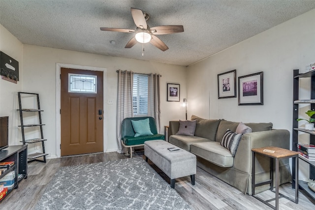 living room with hardwood / wood-style flooring, ceiling fan, and a textured ceiling