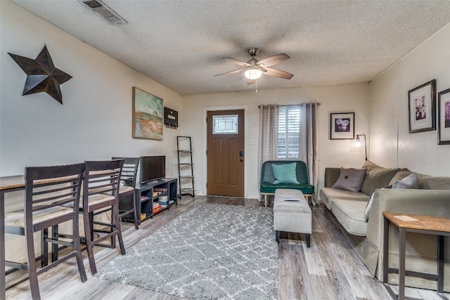 living room with a textured ceiling, ceiling fan, and hardwood / wood-style floors