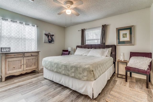 bedroom with ceiling fan, light hardwood / wood-style floors, and a textured ceiling