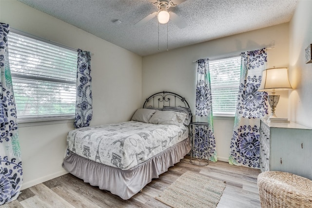 bedroom with a textured ceiling, ceiling fan, and light wood-type flooring