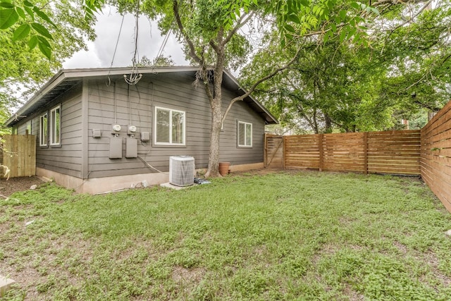 rear view of house featuring central AC and a lawn