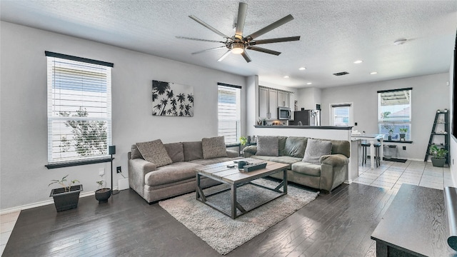 living room featuring a textured ceiling, ceiling fan, and light hardwood / wood-style floors