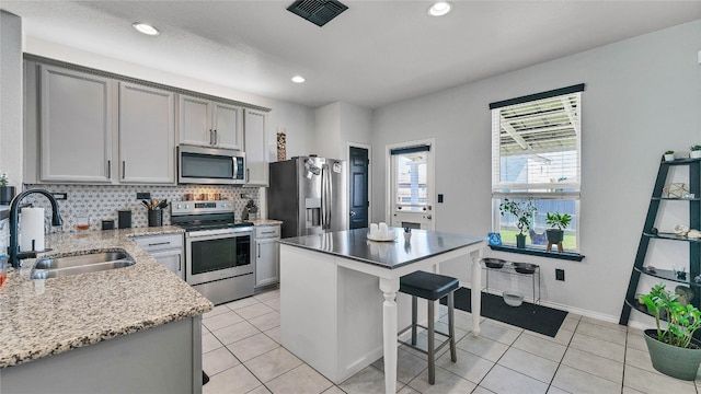 kitchen featuring a kitchen island, stainless steel appliances, sink, and light tile flooring