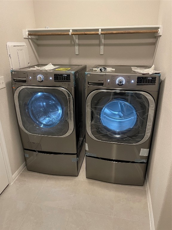 laundry area with washer and dryer and light tile flooring