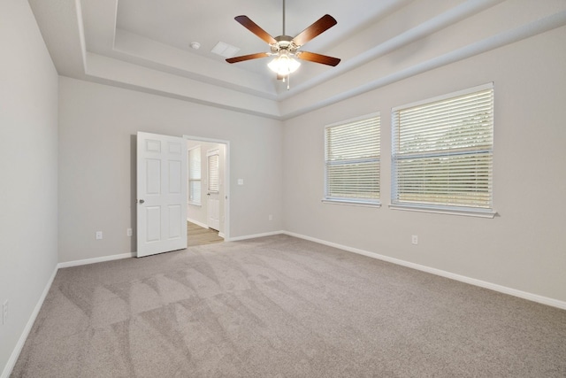 empty room featuring carpet, ceiling fan, and a tray ceiling