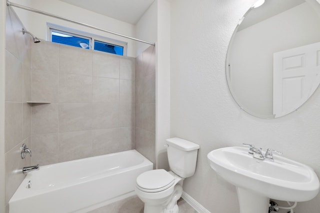 full bathroom with sink, tiled shower / bath combo, and toilet