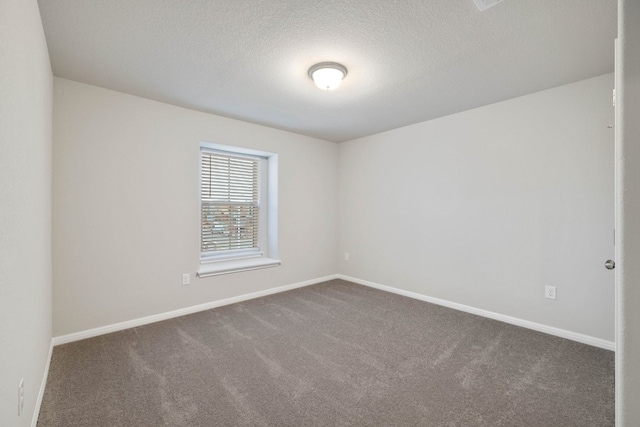 spare room with dark carpet and a textured ceiling