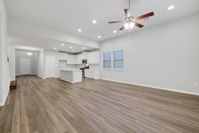 unfurnished living room with light hardwood / wood-style floors, ceiling fan, and sink