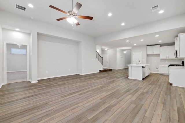 unfurnished living room with sink, ceiling fan, and light hardwood / wood-style flooring