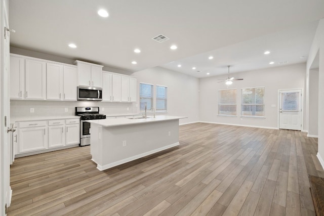 kitchen featuring light hardwood / wood-style flooring, stainless steel appliances, sink, a center island with sink, and ceiling fan