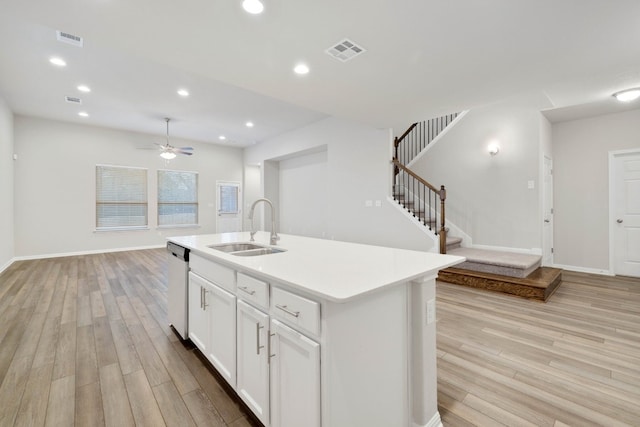 kitchen with ceiling fan, an island with sink, sink, light wood-type flooring, and stainless steel dishwasher