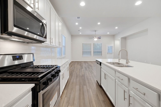 kitchen featuring white cabinets, sink, tasteful backsplash, stainless steel appliances, and light hardwood / wood-style flooring