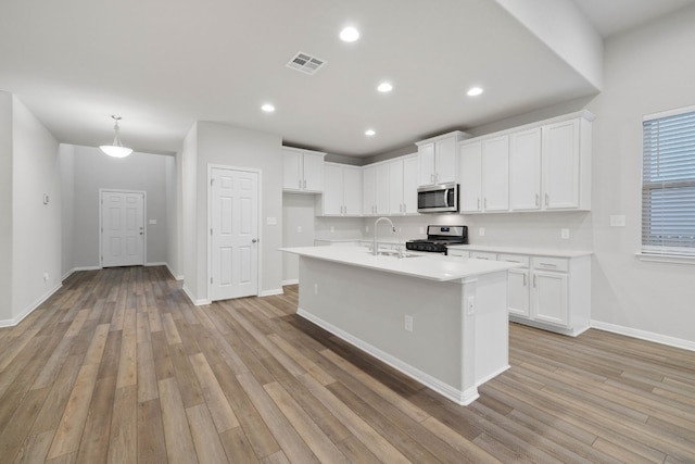 kitchen with white cabinets, light hardwood / wood-style floors, and appliances with stainless steel finishes