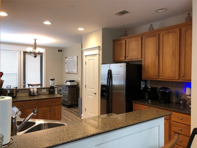 kitchen with sink, backsplash, stainless steel fridge, light hardwood / wood-style flooring, and an inviting chandelier