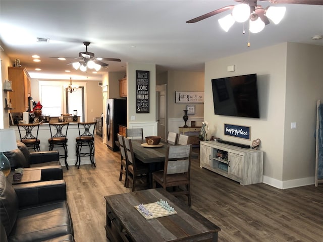 living room featuring ceiling fan with notable chandelier and hardwood / wood-style flooring