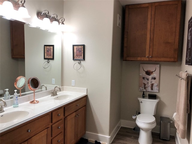 bathroom with dual sinks, wood-type flooring, toilet, and large vanity