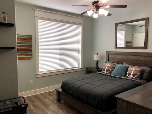 bedroom featuring ceiling fan, dark hardwood / wood-style floors, and multiple windows