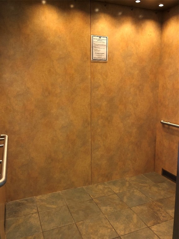 room details featuring elevator and dark tile flooring