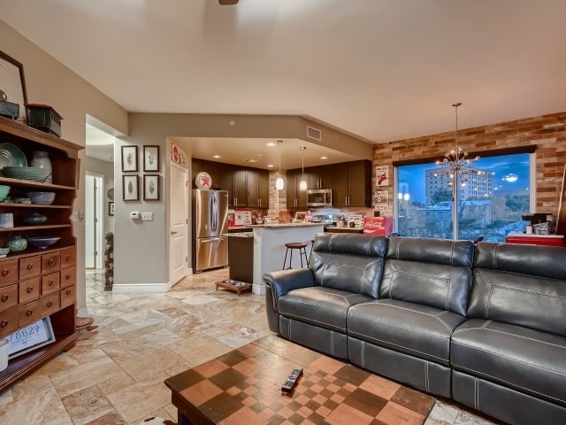 tiled living room featuring brick wall and an inviting chandelier