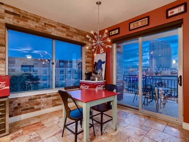 tiled dining room with brick wall and a notable chandelier