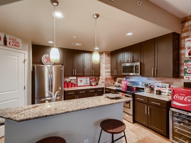 kitchen with beverage cooler, appliances with stainless steel finishes, backsplash, and decorative light fixtures