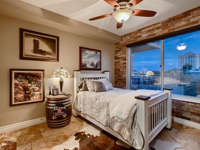 tiled bedroom featuring brick wall, ceiling fan, and access to exterior