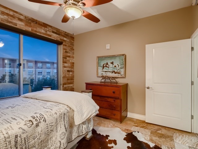 tiled bedroom featuring brick wall and ceiling fan