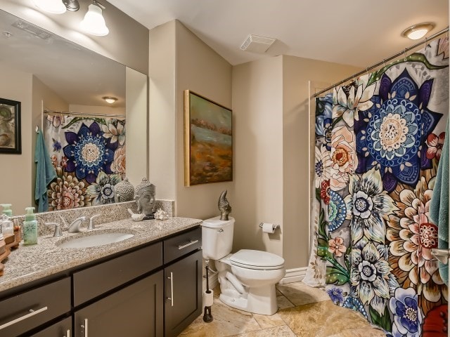 bathroom featuring toilet, tile flooring, and vanity