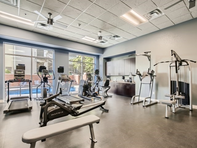 exercise room featuring ceiling fan and a paneled ceiling