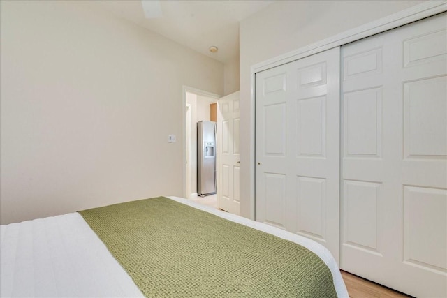 bedroom featuring a closet, stainless steel fridge with ice dispenser, and wood-type flooring