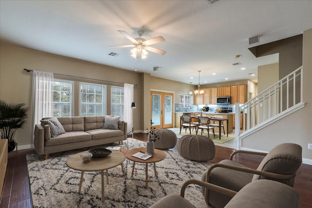 living room with ceiling fan with notable chandelier, dark hardwood / wood-style flooring, and french doors