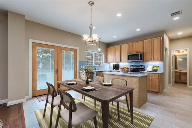 kitchen featuring a kitchen island, stainless steel appliances, tasteful backsplash, an inviting chandelier, and hanging light fixtures