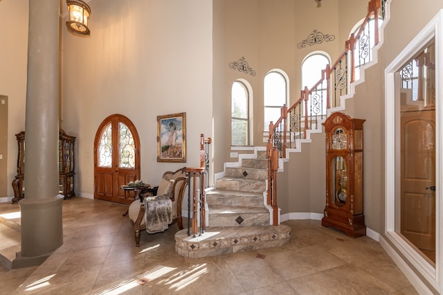 entrance foyer featuring a towering ceiling, decorative columns, and plenty of natural light