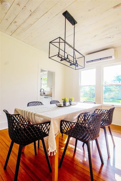 dining space with a healthy amount of sunlight, a wall unit AC, and hardwood / wood-style floors