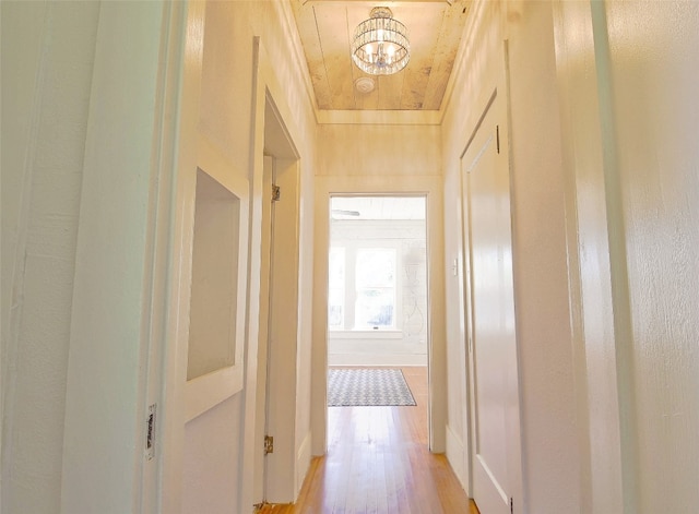 hall with light hardwood / wood-style flooring and an inviting chandelier