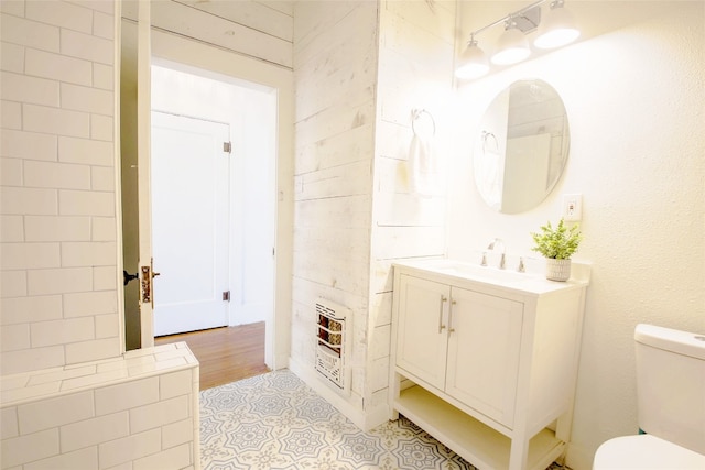 bathroom featuring heating unit, vanity, hardwood / wood-style flooring, and toilet