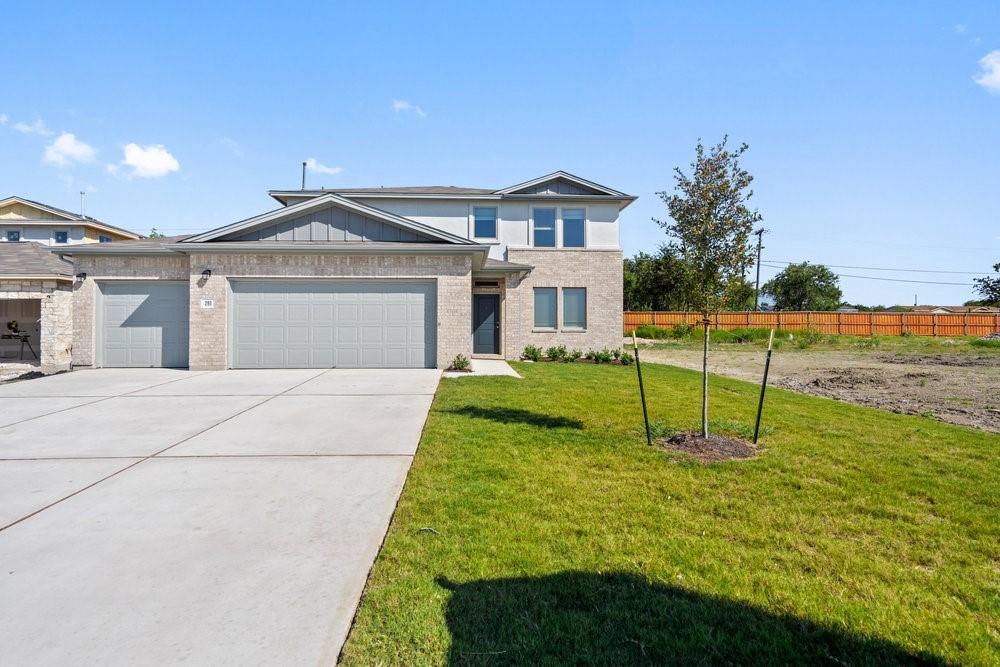 view of front of property featuring a garage, concrete driveway, fence, a front lawn, and brick siding