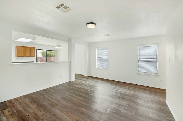 unfurnished room with a notable chandelier and dark wood-type flooring