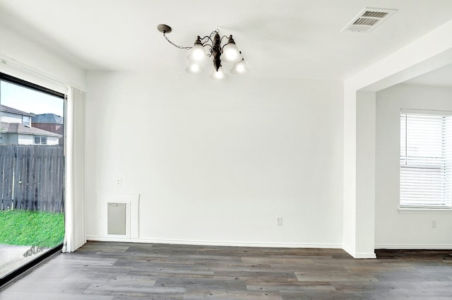 spare room featuring wood-type flooring and an inviting chandelier