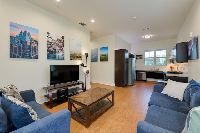 living room featuring sink and light hardwood / wood-style flooring