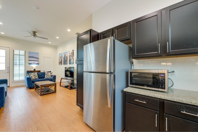 kitchen with tasteful backsplash, ceiling fan, light stone countertops, appliances with stainless steel finishes, and light hardwood / wood-style flooring