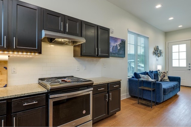 kitchen with stainless steel range with electric stovetop, tasteful backsplash, light wood-type flooring, and light stone countertops